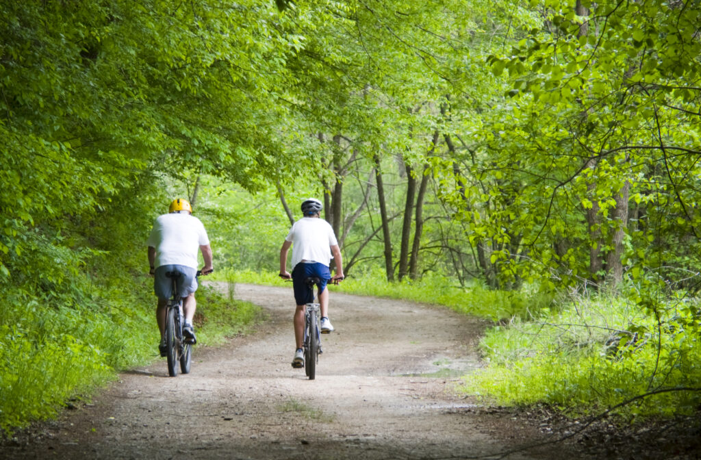 Two bikers riding on a dirt trail through the trees in Hunterdon County