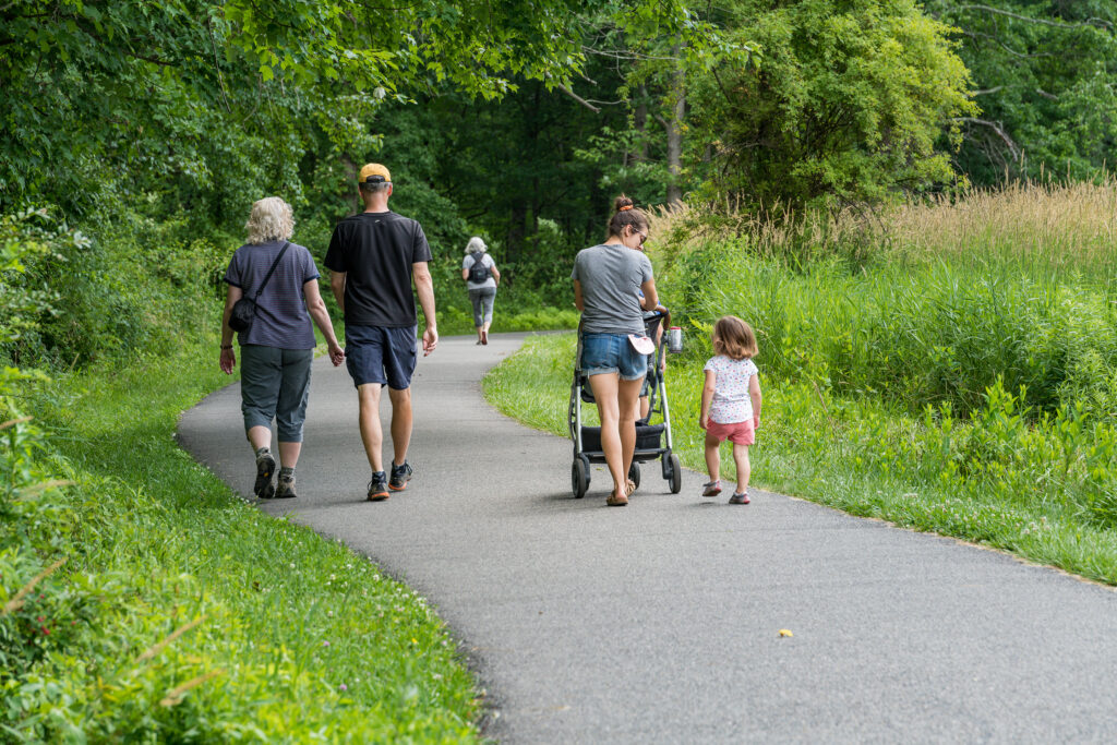 A multi-generational family walks down a paved nature trail.