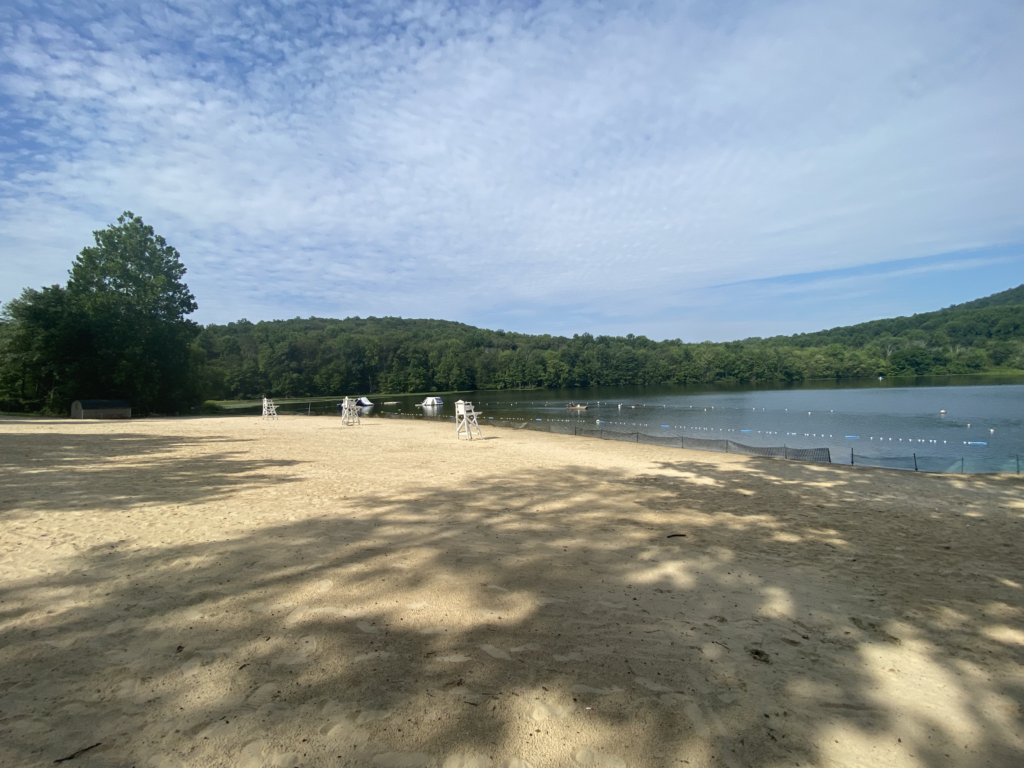 sandy beach with lake swimming area in wooded surroundings