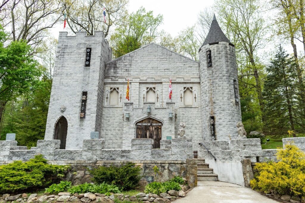 Exterior of historic white stone building with a turret and a tower. Home of the Pac Amicus Theater.